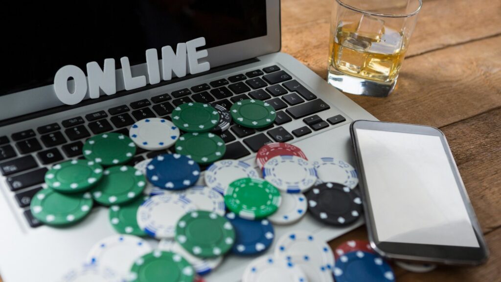 Laptop met het woord ONLINE, casinofiches en een smartphone