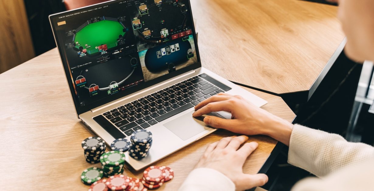 Young man play online poker in laptop. Unrecognizable person.